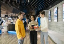 A group of friends enjoying popcorn and conversation in a modern cinema hallway.