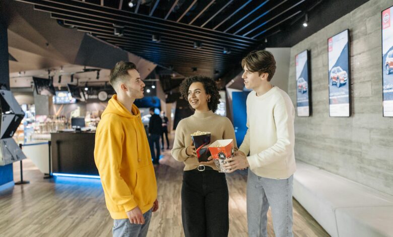 A group of friends enjoying popcorn and conversation in a modern cinema hallway.