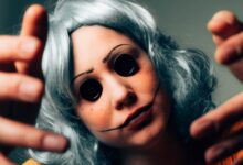 Creepy close-up of a woman in disguise, featuring button eyes and a painted face for a horror effect.