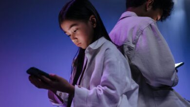 Two children engrossed in using their smartphones in a dimly lit setting.