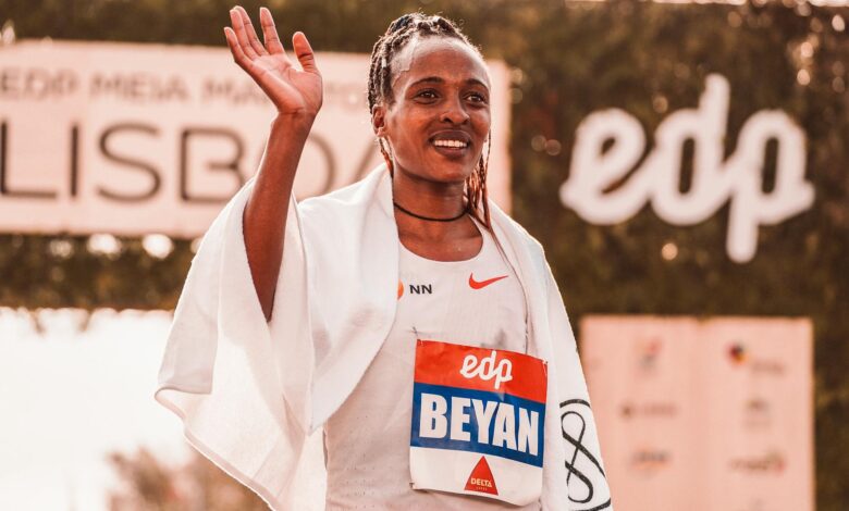 Triumphant female marathon runner celebrates victory wrapped in towel outdoors.
