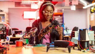 Black female engineer at desk assembling drones, showcasing electronics and technology in a modern lab setting.
