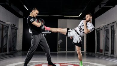 Two men practice kickboxing in a professional gym environment, showcasing dynamic movement and sport.