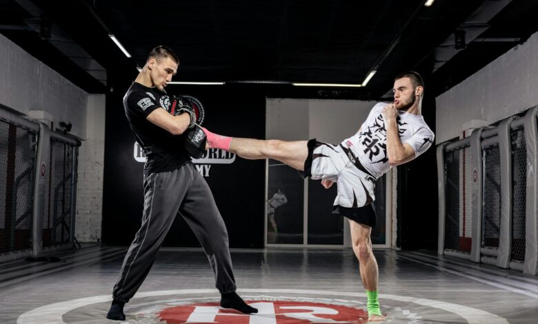 Two men practice kickboxing in a professional gym environment, showcasing dynamic movement and sport.