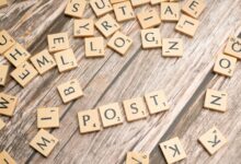 Wooden scrabble tiles scattered with the word 'POST' on a rustic wooden surface.