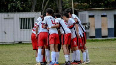 Young soccer players huddle on field in team uniform before game.