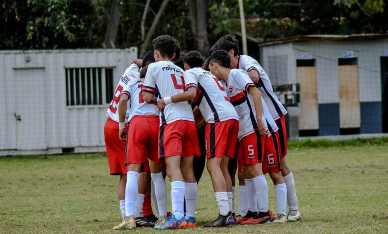 Young soccer players huddle on field in team uniform before game.