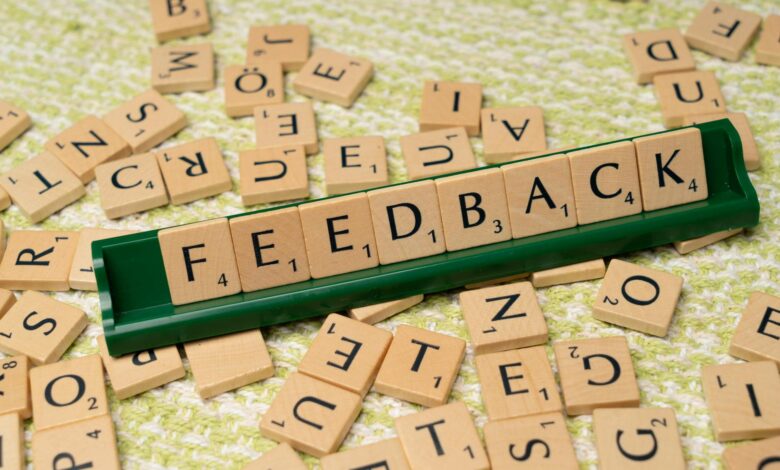 Wooden letter tiles spelling 'feedback' on a green rack, representing communication and evaluation.