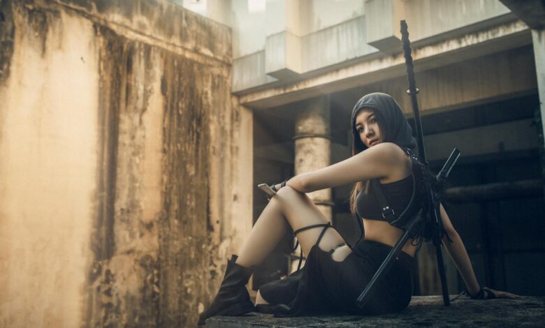 A woman in tactical gear poses in an abandoned urban setting, exuding strength and mystery.