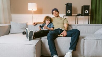 Father and son spending quality time playing video games on couch.