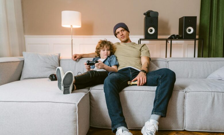 Father and son spending quality time playing video games on couch.