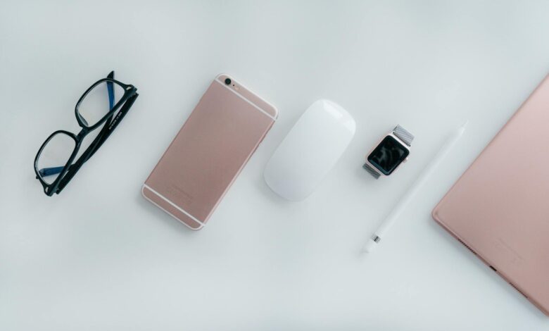 Elegant arrangement of glasses, phone, watch, mouse, pencil, and tablet on a white surface.