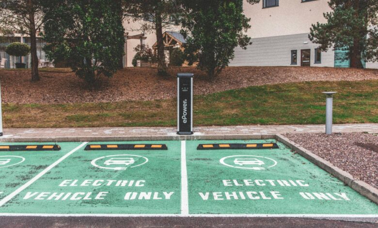 Green electric vehicle parking with charging station in urban environment.
