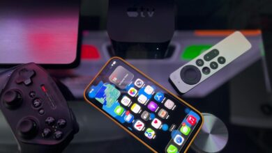 Stylish home entertainment setup featuring an iPhone, Apple TV, and gaming controller on a dark surface.