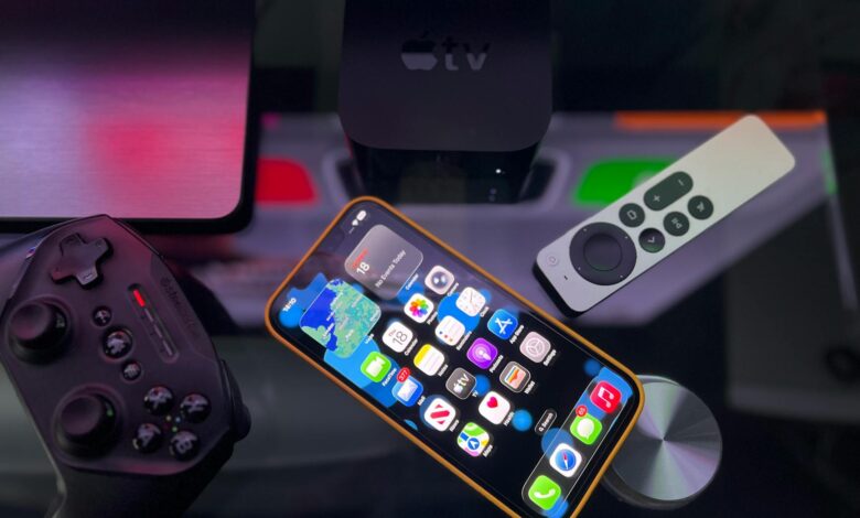 Stylish home entertainment setup featuring an iPhone, Apple TV, and gaming controller on a dark surface.