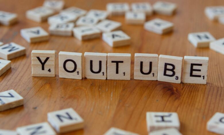 Wooden letter tiles spelling 'YOUTUBE' on a wooden surface, symbolizing video sharing and streaming.