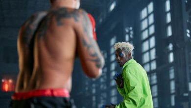 Two fighters engaged in cosplay-themed martial arts sparring inside a warehouse.