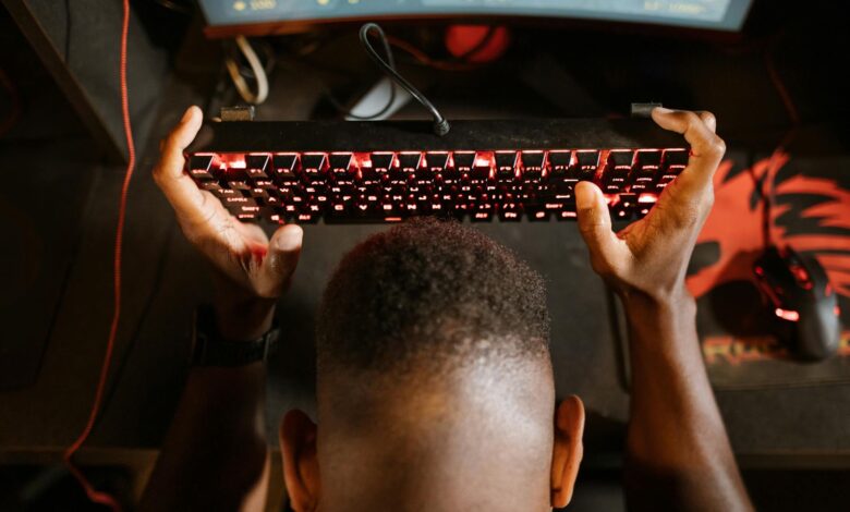 Gamer expresses frustration with video game by holding up keyboard. Overhead shot of gaming setup.
