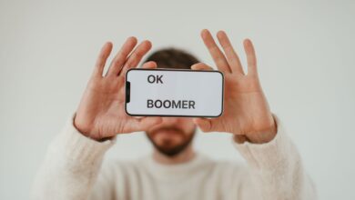 A man holding a smartphone with 'OK Boomer' text, emphasizing generational themes and internet culture.
