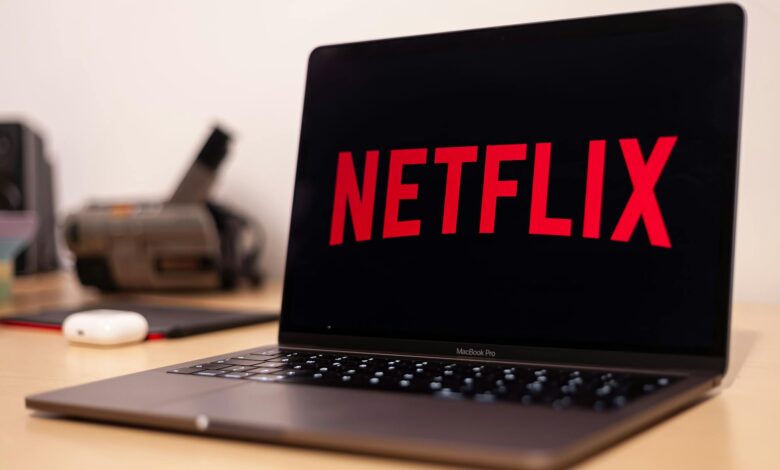 Close-up of a MacBook Pro showing Netflix on the screen in a modern workspace.