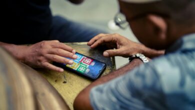 Two individuals play a mobile game on a smartphone outdoors in Jakarta, Indonesia.
