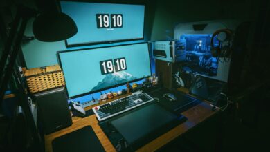A sleek gaming desk setup featuring dual monitors, keyboard, and gaming PC in a dimly lit home office.