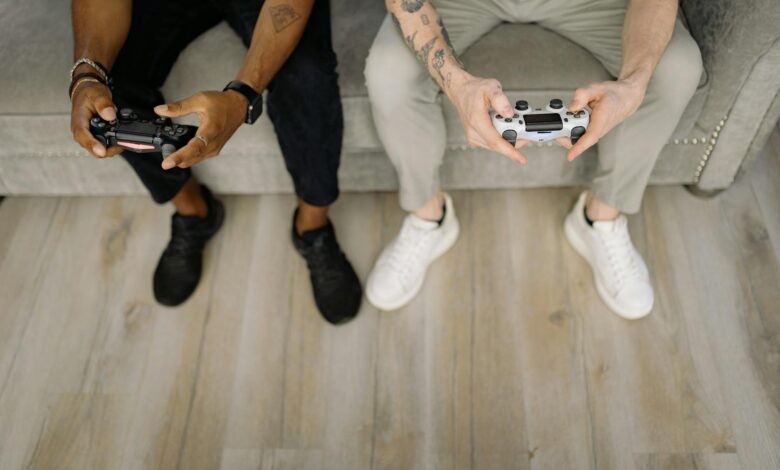 Two friends with gaming controllers focusing on a video game indoors from above.