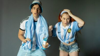 Excited Argentine fans in team jerseys, intently watching a sports event indoors.
