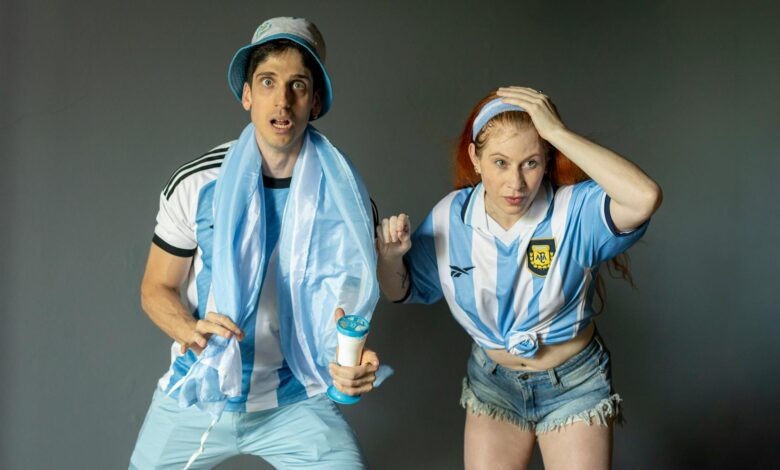 Excited Argentine fans in team jerseys, intently watching a sports event indoors.
