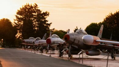 Row of vintage fighter jets showcased outdoors at sunset, offering a nostalgic glimpse of military aviation history.