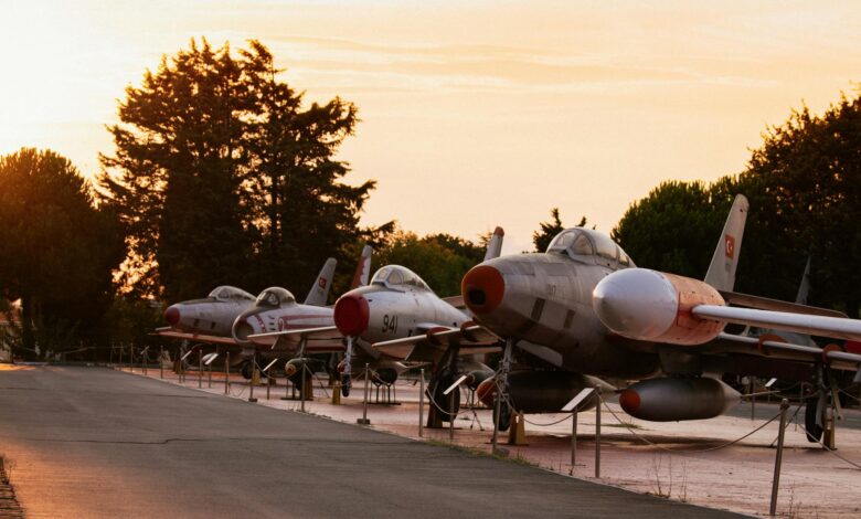 Row of vintage fighter jets showcased outdoors at sunset, offering a nostalgic glimpse of military aviation history.