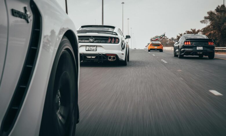 Dynamic view of sports cars racing on a highway, showcasing speed and motion.