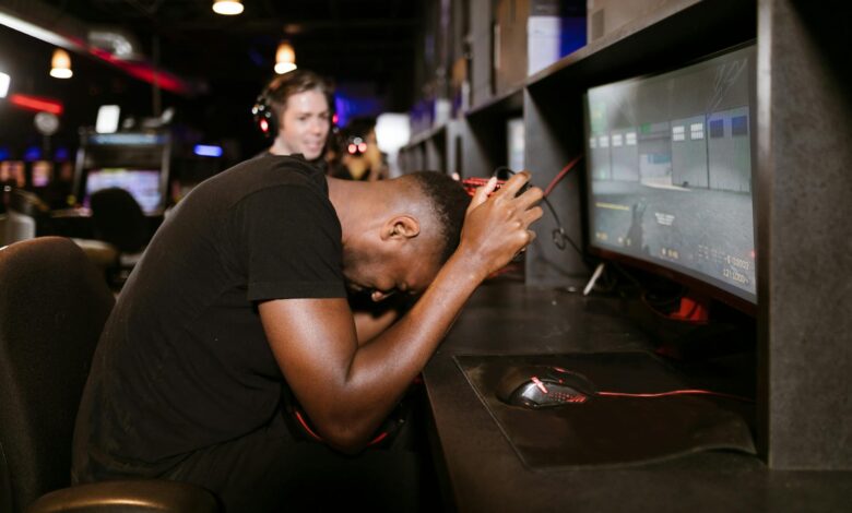 An adult male gamer shows frustration while playing a computer game in an esports arena.
