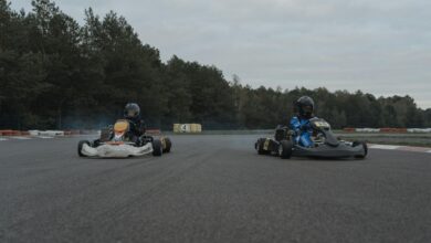 Two racers competing in a thrilling karting race on an outdoor track with forest backdrop.