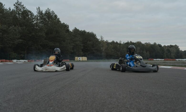 Two racers competing in a thrilling karting race on an outdoor track with forest backdrop.