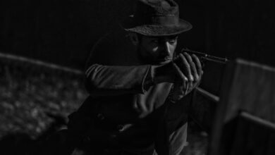 Mysterious man in noir style aiming a pistol with intense focus.
