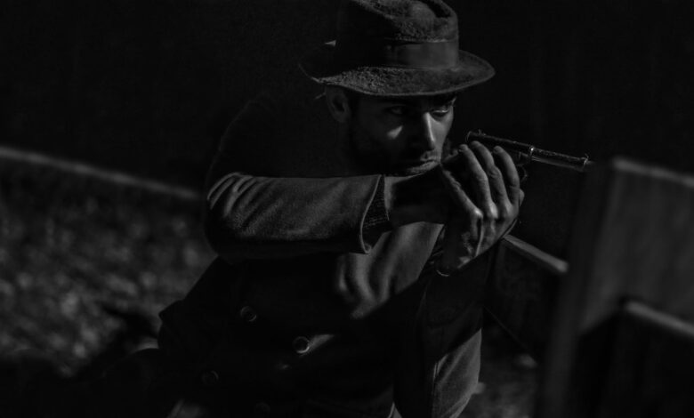 Mysterious man in noir style aiming a pistol with intense focus.