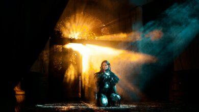 A young woman kneels in dramatic light and shadows, creating an ethereal atmosphere.