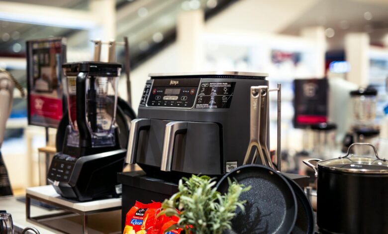 Showcase of modern kitchen appliances in a retail store, featuring blenders and cooking equipment.