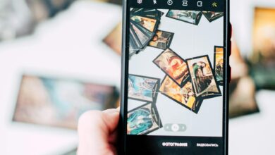 Hand holding smartphone capturing colorful tarot cards in focus.