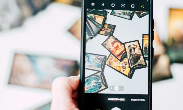 Hand holding smartphone capturing colorful tarot cards in focus.