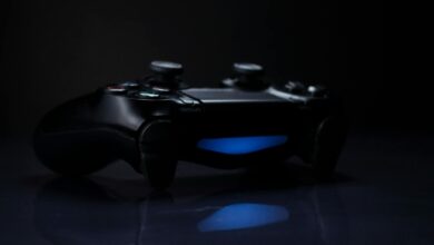 A dark, moody shot of a gaming controller with a glowing blue light reflection.