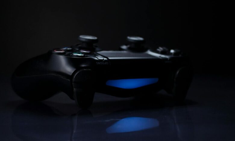 A dark, moody shot of a gaming controller with a glowing blue light reflection.
