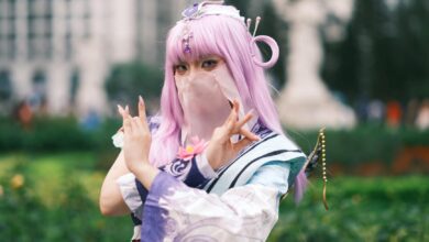 Cosplay enthusiast poses in colorful attire with lavender hair outdoors in Vietnam.