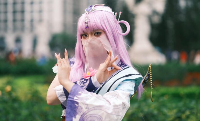 Cosplay enthusiast poses in colorful attire with lavender hair outdoors in Vietnam.
