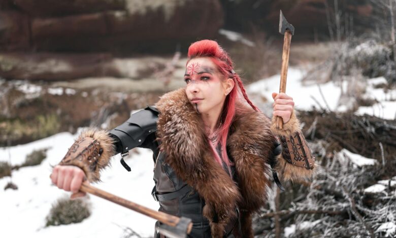 Viking woman in winter armor holding axes, ready for battle; fierce and determined.