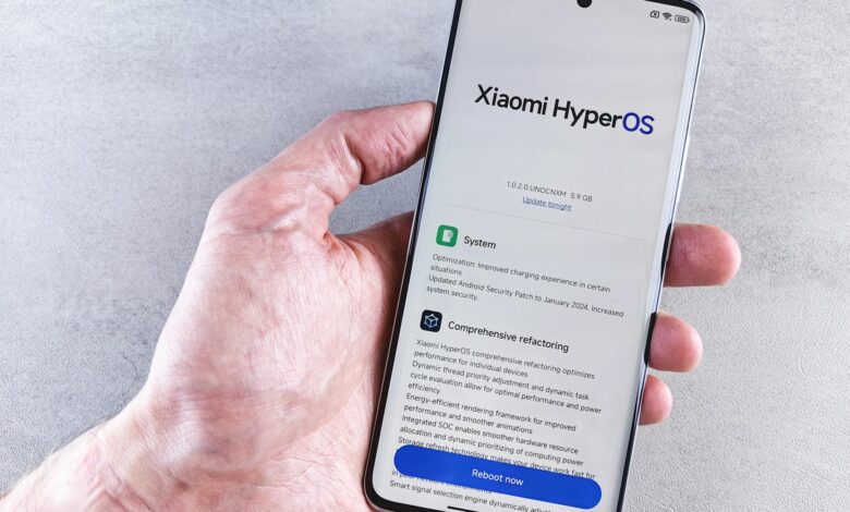 Close-up of a hand holding a Xiaomi smartphone with HyperOS interface, showcasing comprehensive refactoring and system update details.