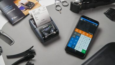 Overhead view of modern black cash register and calculator on smartphone composing with clipper and other tool for cutting hair in barbershop