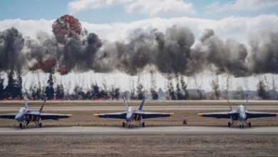 Dynamic scene featuring Blue Angels jets amid smoke and explosions during an airshow demonstration.