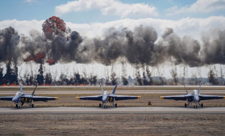 Dynamic scene featuring Blue Angels jets amid smoke and explosions during an airshow demonstration.
